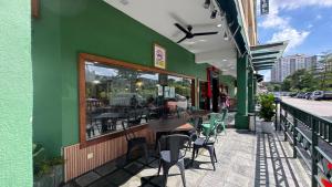 a green building with tables and chairs on a sidewalk at JSD Hotel in Petaling Jaya