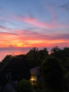 a sunset over the ocean with a house and trees at Reen Run Sunset Private Pool Villa in Ko Phangan