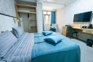 a bedroom with a blue bed with a desk at Onyx Hotel Bishkek in Bishkek