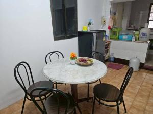 a table with chairs and a bowl of flowers on it in a kitchen at We Hostel in Hat Yai