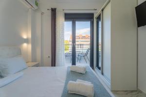 a bedroom with a white bed and a balcony at SithoniaRS Sea Nomad Luxury Maisonette in Nikiti