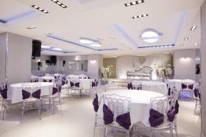 une salle de banquet avec des tables et des chaises blanches ainsi qu'un piano dans l'établissement ktHotels, à Oulad Yaïch