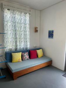 a couch with colorful pillows in front of a window at Eagles Nest Residence - Apartment 2 in Rodrigues Island