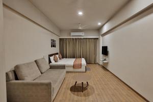a living room with a couch and a bed at Weekend Address By Farmville in Surat