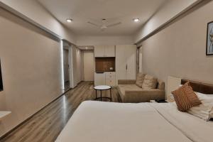 a bedroom with a bed and a couch and a kitchen at Weekend Address By Farmville in Surat +9 photos