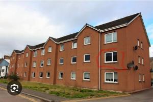 a large red brick building with white windows at Nessy5 Apartment in Inverness