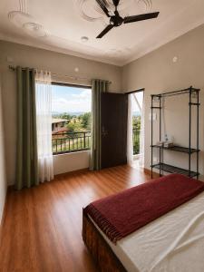 a bedroom with a bed and a large window at Aahista Stays- Mountain view homestay in Bīr