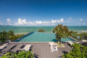 a swimming pool with lounge chairs and the ocean at Bayphere Residence Private Beach With Fitness and Pool in Na Jomtien