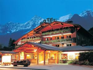 un gran edificio con montañas en el fondo en Chalet Hôtel du Bois en Les Houches