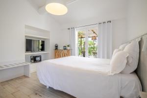 a white bedroom with a large bed and a tv at Mas des Cabidoules in Saintes-Maries-de-la-Mer