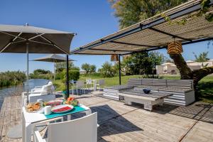 a patio with a table and benches and an umbrella at Mas des Cabidoules in Saintes-Maries-de-la-Mer
