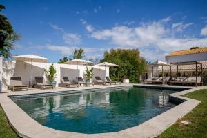 a pool with chairs and umbrellas next to a house at Mas des Cabidoules in Saintes-Maries-de-la-Mer