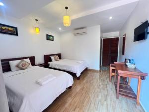 a hotel room with two beds and a desk and a television at Monterey Angkor Boutique in Phum Pobos +3 photos