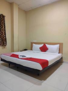 a bedroom with a large bed with red and white pillows at Hotel O CANARIES RETIREES RESIDENCY in Kottakupam +27 photos