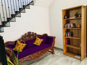 a purple couch with yellow pillows in a living room at Sun and Waves Beach Cottage Ahungalla in Ahungalla