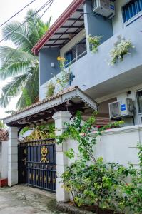 a house with a black gate and a palm tree at Sun and Waves Beach Cottage Ahungalla in Ahungalla