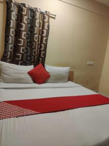 a bed with two red pillows and a curtain at Hotel O CANARIES RETIREES RESIDENCY in Kottakupam