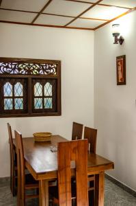 a dining room table and chairs with a wooden table and a window at Sun and Waves Beach Cottage Ahungalla in Ahungalla