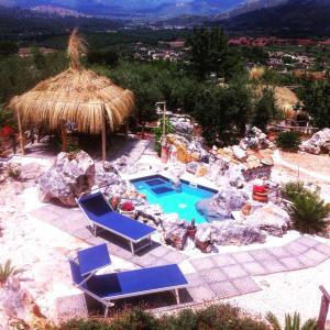 une piscine extérieure avec deux chaises bleues et une cabane en paille dans l'établissement Le Capanne di Villa Margherita, à Sonnino