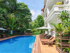 a swimming pool with chairs and umbrellas next to a building at Chateau d'Angkor La Residence in Siem Reap