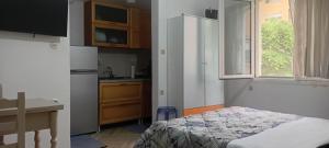 a bedroom with a bed and a kitchen with a window at Enki's Garden in Tirana