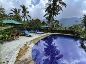 a swimming pool with chairs and umbrellas on a resort at Bali Hidden Lemukih in Sawan