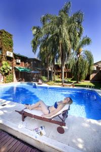 a woman laying on a chaise lounge in front of a swimming pool at Hosteria-Spa Posada del Sol in Libertador General San Martín