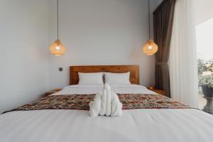 a bed with a pair of white towels on it at Dana's Kelating Guest House, Close to Kelating Beach in Tabanan