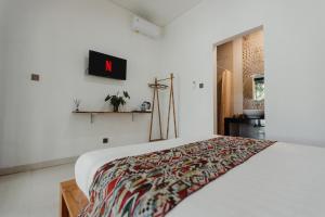 a bedroom with a white bed with a colorful blanket on it at Dana's Kelating Guest House, Close to Kelating Beach in Tabanan