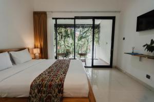a bedroom with a large bed and a sliding glass door at Dana's Kelating Guest House, Close to Kelating Beach in Tabanan