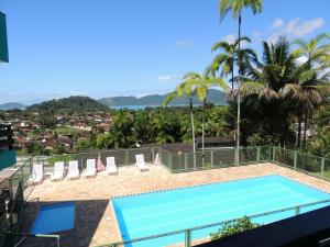 a swimming pool with chairs and a view of a city at Marencanto Pousada in Ubatuba