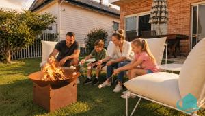 a group of people sitting around a fire pit at Wangi Waterfront Weekender in Wangi Wangi