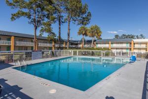 a swimming pool in front of a building with trees at Econo Lodge Thomasville in Thomasville