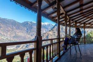 a woman sitting on a porch reading a book at Jhumelo Homestay, Ukhimath in Ukhimath