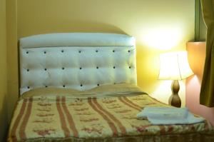 1 dormitorio con 1 cama con cabecero blanco y lámpara en Mama Chelita en Nazca