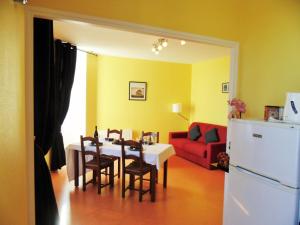 a dining room with a table and chairs and a red couch at Les Gîtes de La Fontaine in Jullié