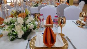 a table with a white table cloth with flowers and glasses at Atlantic Beach Hôtel Bénin in Cotonou