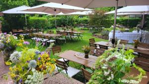 a garden with wooden tables and umbrellas and flowers at Die "Alte Schmelz"- Boutique-Landhotel & Restaurant in Bad Dürkheim