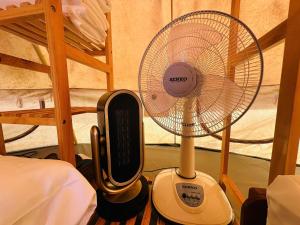 a fan sitting on the floor next to a bed at DaLart Glamping & Coffee in Ấp Ða Lôc