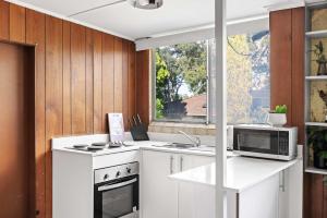 a kitchen with a stove and a microwave at Simple 2-Double Bed Studio Stay at Peakhurst in Peakhurst