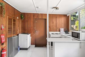 a kitchen with white appliances and wooden walls at Simple 2-Double Bed Studio Stay at Peakhurst in Peakhurst +14 photos