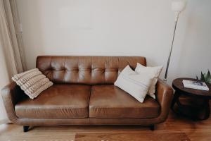 a brown leather couch with two pillows on it at View Street Studios - Tallerack in Albany +1 photo