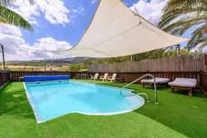 a pool with a large umbrella in a yard at בינות התמרים- 3 צימרים מהממים עם בריכה וג'קוזי ספא! in Menaẖemya