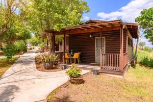 a small cabin with a table and chairs in a yard at בינות התמרים- 3 צימרים מהממים עם בריכה וג'קוזי ספא! in Menaẖemya