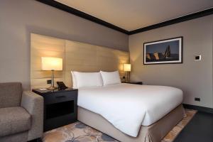 a bedroom with a large white bed and a chair at InterContinental Malta by IHG in St. Julianʼs