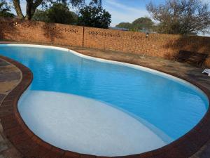 a large blue swimming pool next to a brick wall at Fountainhill Estate Accommodation in Wartburg