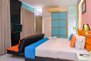 a bedroom with a large bed and a chair at Sans Hotel International Surabaya in Gubeng