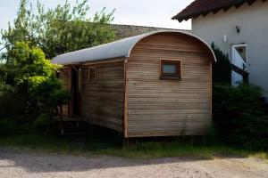 a wooden shed with a gambrel roof next to a house at Pfälzer Zirkuswagen in Ranschbach
