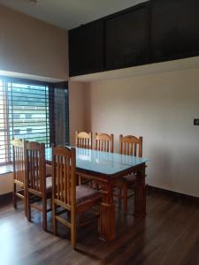 a dining room table with four chairs and a glass table at Sri Skandaa in Sringeri