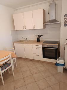a kitchen with white cabinets and a sink and a stove at Apartments Biba & Lucy in Ražanac +52 photos
